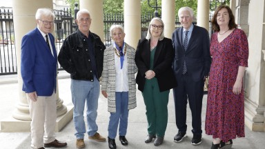 A group of men and women smiling and facing the camera on steps of National Library of Ireland