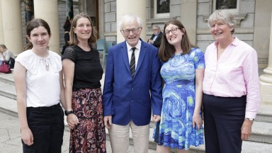 A family of men and women smiling to camera outside National Library of Ireland