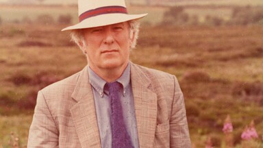 Heaney in a suit standing in a bog