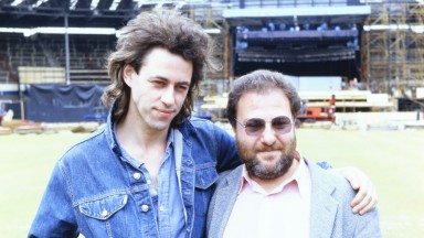 Bob Geldof and Harvey Goldsmith standing on the pitch at Wembley, with construction of the stage behind