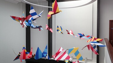 An artwork by Mazer of paper birds taking flight in a spiral