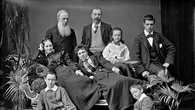 Family group on sofa in a studio with potted plants.