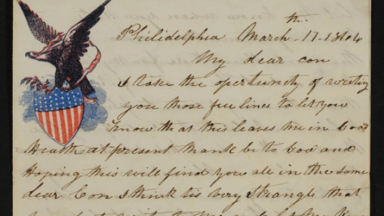 Image of a handwritten letter with an eagle and American flag pendant. 