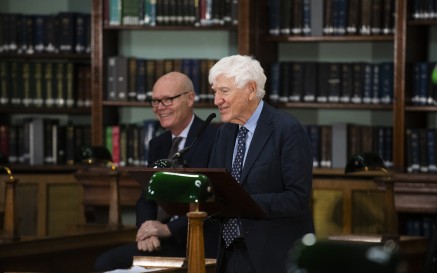 Joseph Hassett ina sheasamh ag póidiam ag labhairt le lucht féachana laistigh de Seomra Léitheoireachta NLI