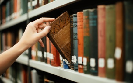 A hand removing a book from a shelf