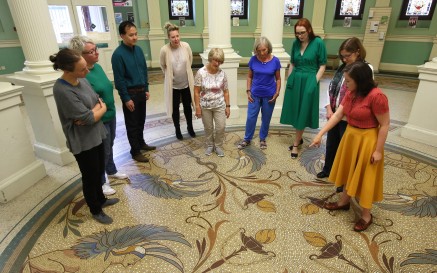 A guide points out a detail in the floor mosaic at the entrance to the National Library of Ireland to a group of visitors