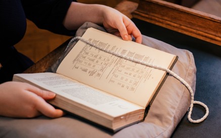 Image of hands holding a book on a cushion