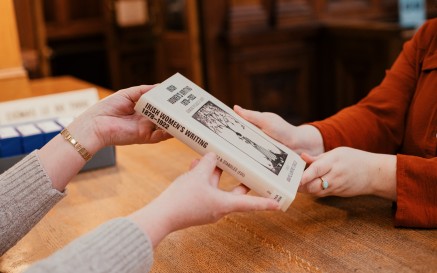 A pair of hands passing a book to another pair of hands