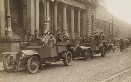 Grianghraf dubh agus bán de dhá ualach carranna na nDúchrónach ag fágáil foirgnimh ar Shráid Amiens 