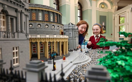 Acting Director Katherine McSharry and child standing next to the front of Lego model of NLI