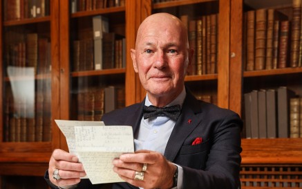 Bernárd Lynch seated in boardroom holding papers