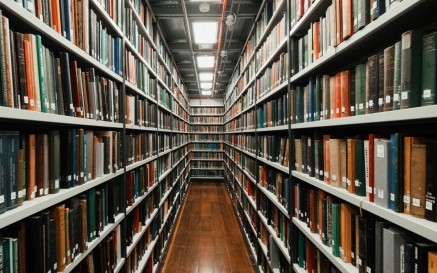 View down a book aisle with shelves lined from floor to ceiling with books