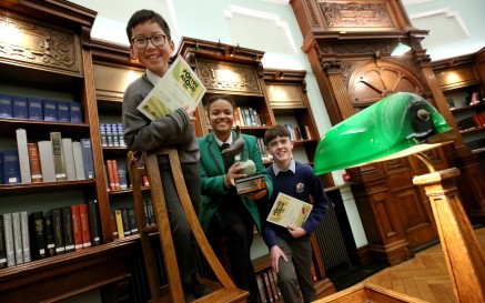 George Pham, Ellie Reynolds and Shay Collins standing on ladder in the NLI's Reading Room