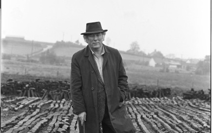 Seamus Heaney standing in the bog leaning on a wooden walking stick