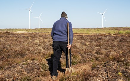 An image of person in a warm jumper in hat as they walk across the bog