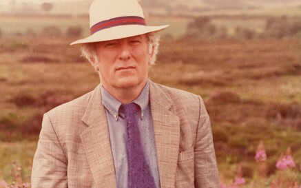 Heaney in a suit standing in a bog