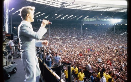 David Bowie performing at Wembley, with audience and photography pen in background