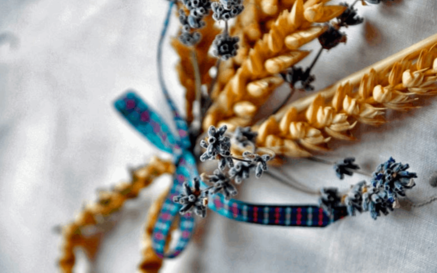 An image showing a harvest bow, which is wheat stalks and lavender weaved into a bow tied together by a ribbon
