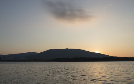 Sunset over Belfast Lough with calm water and a silhouetted ridge on the horizon.
