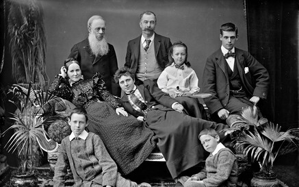 Family group on sofa in a studio with potted plants.